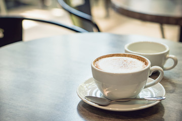 Hot coffee and hot tea place on the marble table in early morning with copyspace, white cup and silver spoon.