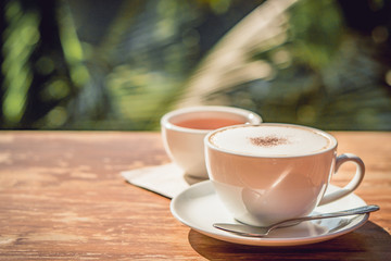 Hot coffee and hot tea place on the wooden table in early morning with copyspace, white cup and silver spoon.
