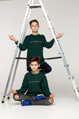 Two attractive guys in green sweaters meditating together