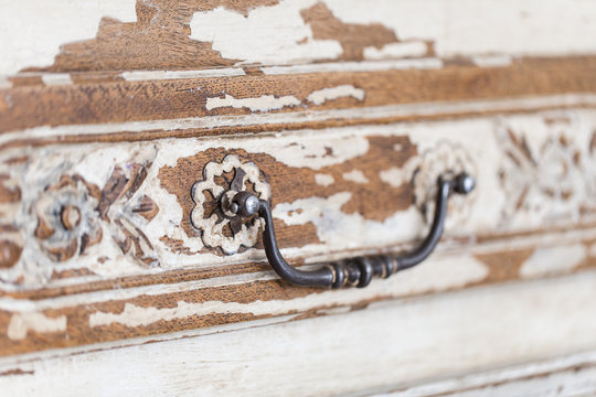Vintage chest of drawers with carving white color with fading and metal handle. Close-up. Selective focus