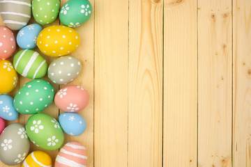 Colorful pastel Easter Egg side border against a natural wood background. Top view with copy space.