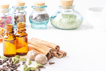 Essential oils in glass bottles maid from spices and nutmeg, cardamon, cinnamon, clove on wooden background