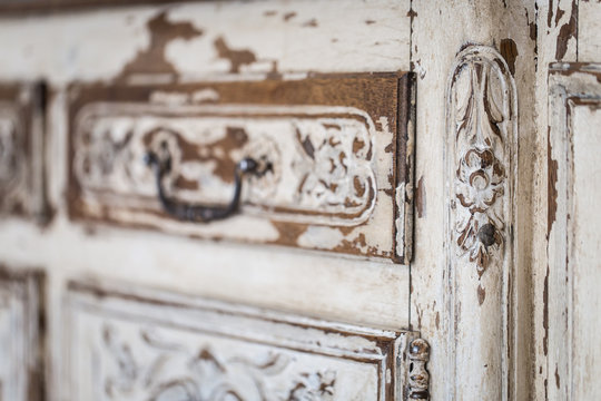 Vintage chest of drawers with carving white color with fading and metal handle. Close-up. Selective focus