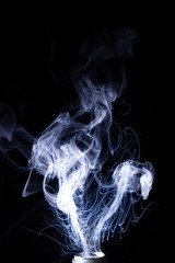 Vape smoke clouds isolated on black background. Hot vape liquid splash in vape coil. Nice aromatic cloud. Low light photo. Underexposed photo in a low key style.