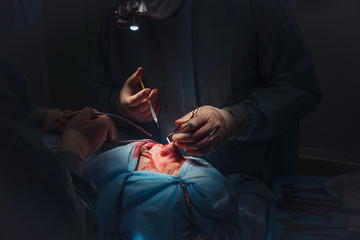 Surgeon and his assistant performing cosmetic surgery on nose