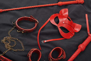 BDSM leather kit. Top view of red bdsm leather set: handcuffs, whip, mask