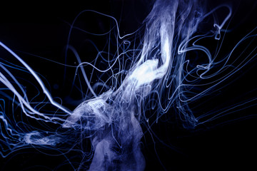 Vape smoke clouds isolated on black background. Hot vape liquid splash in vape coil. Nice aromatic cloud. Low light photo. Underexposed photo in a low key style.