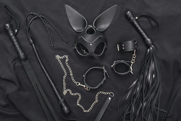 Explore the world of kinky play. Top view of bdsm leather kit (whips, handcuffs, mask and chain)...