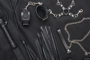 50 Shades of Grey. Top view of bdsm leather kit (whips, handcuffs, mask and chain) against of a...