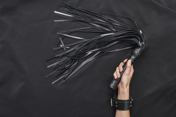 Explore each other's. Top view of female hands in black leather handcuffs holding a whip against of...
