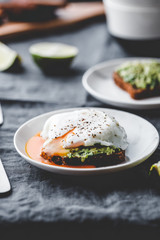 Avocado sandwich with rye bread and a poached egg on a plate. The concept of healthy balanced breakfast.