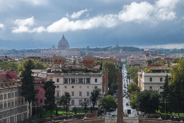 Obraz premium The view of Rome with Sain Peter's Dome in the distance under the grey stormy and cloudy sky, shot from a high point - Terazza del Pincio