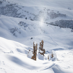 Glittering snowflakes above rocks on a beautiful sunny day in pristine alpine landscape. Calm and...