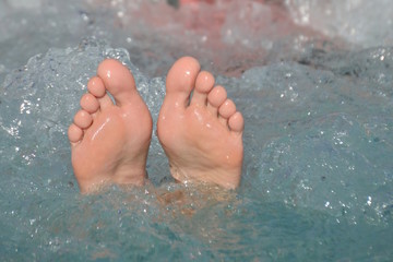 female bare feet out of bubbling water in a whirlpool outdoors in summertime in vacation