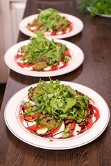 Plates with ready-made salad with tomatoes, mozzarella, Basil on the kitchen serving table