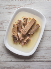 Pieces of canned tuna in olive oil on a plate.