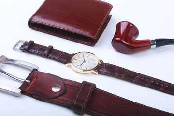 Men's accessories for business and rekreation. Leather belt, wallet, watch and smoking pipe on white background.. Top view composition.