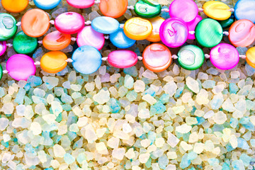 Fototapeta na wymiar Colorful Pearl Beads on Crystals of Aromatic Bath Sea Salt for Spa