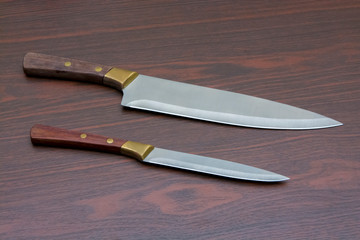 two kitchen knives of different sizes on a wooden table