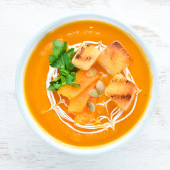 Pumpkin cream soup in a bowl, with toast bread. Dietary food. Top view. Free copy space.