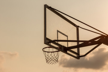 basket ball board under sky with white clouds. Basketball court with old backboard. sky and white clouds on background. Old basket ball Stadium.  basketball hoop in sky background on evening.