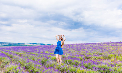 Girl in blue dress on lavender field in cloudy weather
