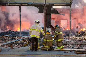 Firemen on knees resting after fighting fire