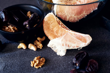 Still life of carelessly scattered grapefruit slices and pomelo at grey background.