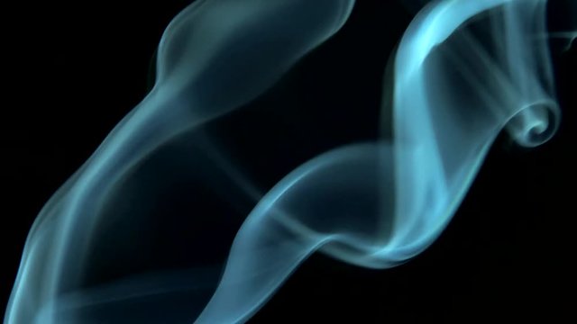 Trickle of smoke slowly rising white light, graceful twists on black background blowing from bottom to top. Closeup