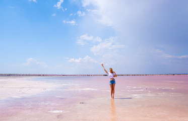 Girl in shorts and t-shirt on the pink salty lake 