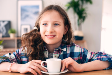 happy kid girl drinking tea for breakfast. Indoor portrait of 9 years old child