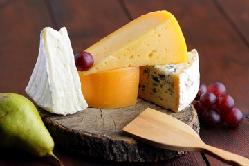 Cheese, pears and grapes on wooden boards. Various types of cheese and fruits on blurred...