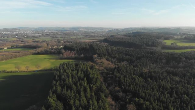 Drone moving forwards over green British countryside & forests