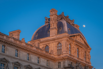 Obraz premium Paris, France - 02 17 2019: The roofs of the buildings of the Louvre Museum at sunset with moon
