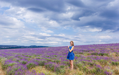 Girl in blue dress on lavender field in cloudy weather