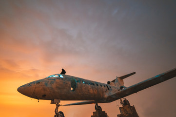 Old airplane at the moon night.  Man sitting on the top of old plane. 