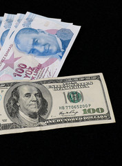 100 Turkish Lira and 100 USD banknote, black background, side by side,