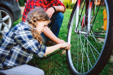 father and daughter fixing problems with bicycle outdoor in summer. Kid girl spending time together...