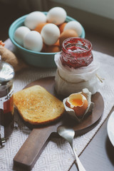 country cottage kitchen with breakfast on wooden table. Toast with jam, farm eggs and coffee