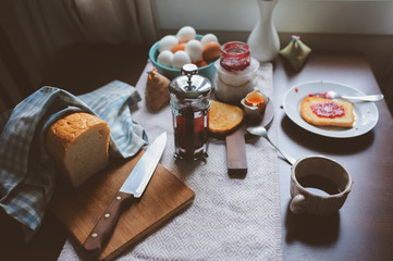 country cottage kitchen with breakfast on wooden table. Toast with jam, farm eggs and coffee