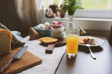 country cottage kitchen with breakfast on wooden table. Toast with jam, farm eggs and coffee