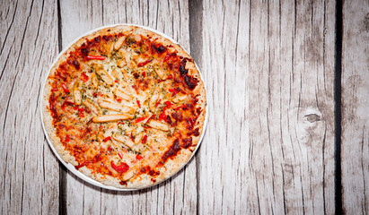 Pizza on a wooden background. Pizza with chicken and cheese on a white background. The concept of eating pizza, preparing a quick dish for guests.