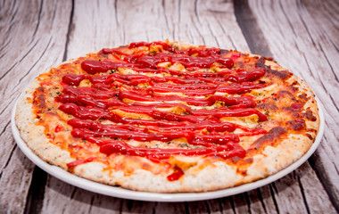 Pizza with ketchup on a wooden background. Pizza with chicken and cheese on a white background. The concept of eating pizza, preparing a quick dish for guests.