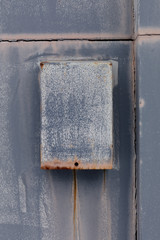 A rusting mail box on an abandoned building.