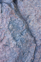 Texture of granite close up. Granite rock with reddish color. Background from solid stone. Pattern with natural material
