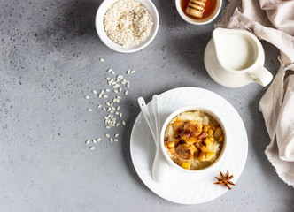 Rice pudding or porridge and fruits (apple, pear, banana and raisins) with honey or maple syrup and spices. Healthy breakfast or dessert.  