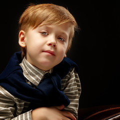 Beautiful little boy on a black background, close-up.