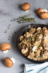 Meat stewed with mushroom and thyme in a cast-iron pan.  Grey concrete background. Copy space. 