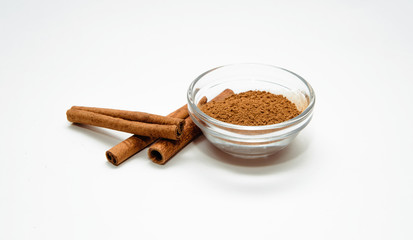 Ground and cinnamon sticks on a white background. Cinnamon is placed on a white table. The concept of using seasonings for dishes. Eating spiced dishes.