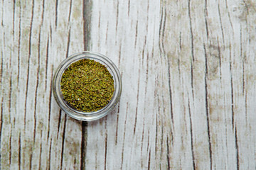 Top view Dried basil in a bowl on a wooden background. Dried lilac lying on a white table. The concept of using seasonings for dishes. Eating spiced dishes.